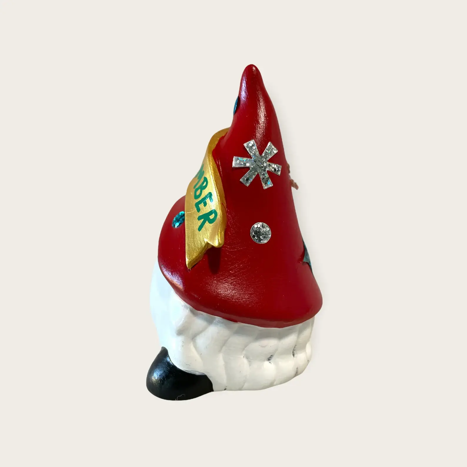 Birthday Gnome for December wearing red hat with snowflakes, and a gold banner across that reads December in Green, Left.