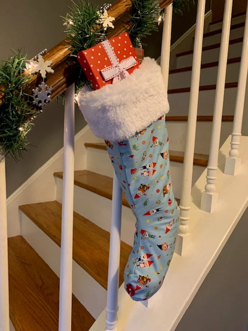 Full light blue Gnome Christmas Stocking with gifts inside, hanging on banister, Front Angle 2